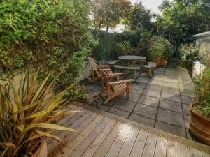a patio with a wooden table and chairs and plants at Min Y Ffordd in Goodwick