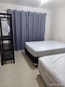 1 dormitorio con 2 camas y cortina azul en Casa Duplex com Vista pro Mar en Guaratuba