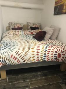 a bed with a colorful comforter and pillows on it at Studio individuel près de Paris in Mantes-la-Jolie