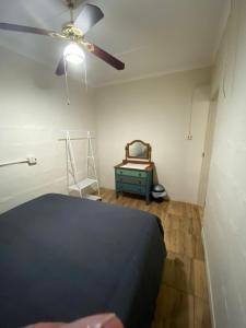 1 dormitorio con ventilador de techo y mesa azul en Dickens Garden Flat en Empangeni