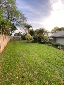 a yard with a fence and a green lawn at Dickens Garden Flat in Empangeni