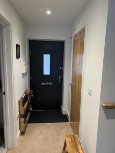 a hallway with a black door and a wooden table at Cozy room in new build, peaceful village location in Cambridge