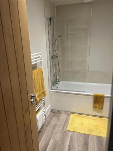 a bathroom with a shower and a tub with a yellow rug at Cozy room in new build, peaceful village location in Cambridge