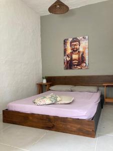 uma cama num quarto com um quadro na parede em SURF PARADISE apartamentos em Pinheira