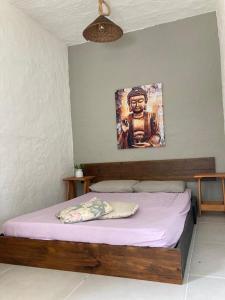 a bed in a bedroom with a painting on the wall at SURF PARADISE apartamentos in Pinheira