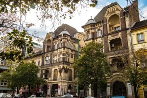 a large building on a city street with trees at Exclusive Apartmanok Szeged in Szeged