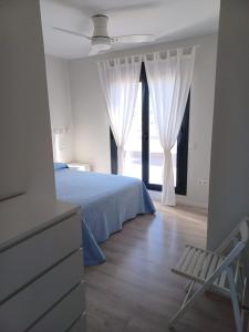 sypialnia z łóżkiem, krzesłem i oknem w obiekcie Atico Costa Doñana w mieście Sanlúcar de Barrameda