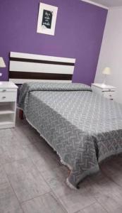 1 dormitorio con 1 cama con pared morada en Casa con parrilla en barrio Fonavi en Federación