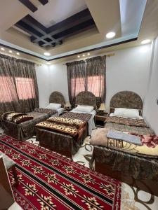 a room with three beds and a rug at Beida Bedouin House in Al Ḩayy
