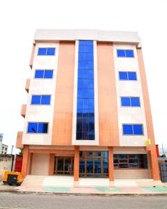 un grand bâtiment avec des fenêtres bleues sur une rue dans l'établissement HOTEL MAVILLA Cotonou, à Cotonou
