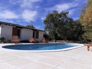 una piscina en un patio con sillas y una casa en Gîte en pleine nature, A la douceur des Chênes, en Maubec
