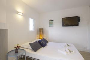 1 dormitorio con 1 cama blanca y TV en la pared en Large studio with ocean view 5 min to Anglet beach - Welkeys, en Anglet