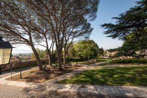 uma passagem num parque com árvores e bancos em Rooms Relais Art Borgocastello3 em Gorizia