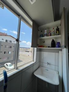 a bathroom with a sink and a window with a view of the beach at 01 APTO em frete ao Shopping Pátio Norte in São-José-do-Ribamar