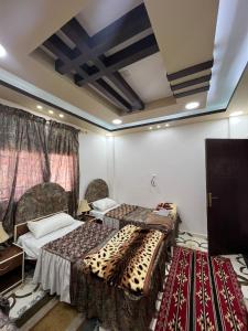 a room with two beds and two tables in it at Beida Bedouin House in Al Ḩayy