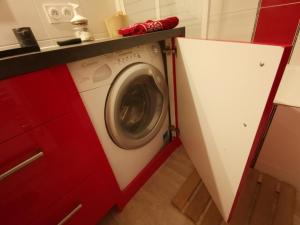 a washing machine in a kitchen with a red cabinet at Appartements T2 et T3 L'esprit chalet au coeur du centre ville et 80 m de la télécabine in Font-Romeu