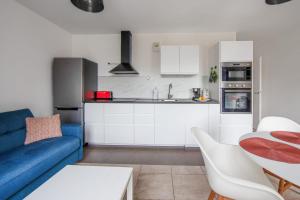 ein Wohnzimmer mit einer blauen Couch und einer Küche in der Unterkunft Appartement Veil - Welkeys in Clichy