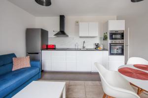 a living room with a blue couch and a kitchen at Modern flat near Montmartre at the doors of Paris in Clichy - Welkeys in Clichy