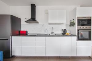 eine weiße Küche mit einer Spüle und einem Herd in der Unterkunft Appartement Veil - Welkeys in Clichy