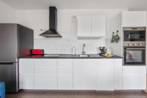 a white kitchen with a sink and a stove at Modern flat near Montmartre at the doors of Paris in Clichy - Welkeys in Clichy