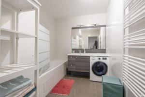 ein weißes Badezimmer mit einer Waschmaschine und einem Waschbecken in der Unterkunft Appartement Veil - Welkeys in Clichy + 4 Fotos