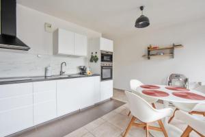 eine Küche mit weißen Schränken und einem Tisch und Stühlen in der Unterkunft Appartement Veil - Welkeys in Clichy