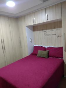 um quarto com uma grande cama rosa e armários em Apartamento mobiliado e aconchegante no Rio de Janeiro