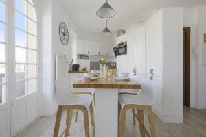 a kitchen with a wooden table and white chairs at Studio Limpo - Welkeys in Hendaye +4 photos