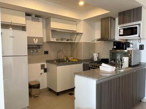 a kitchen with white cabinets and a white refrigerator at Moderno Depto con Vista al Mar in Comodoro Rivadavia