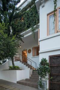 una casa blanca con escaleras y un árbol en Leclerc Hotel Boutique Cali Granada en Cali