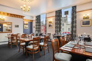 a restaurant with wooden tables and chairs and large windows at Castle Hotel Haverfordwest in Haverfordwest