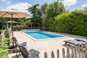a swimming pool with chairs and an umbrella at Chambres d'hôtes Maison Les Galettes in Rezay