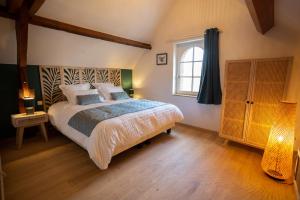 ein Schlafzimmer mit einem großen Bett und einem Fenster in der Unterkunft La Ferme du P'tit Colibri in Gury