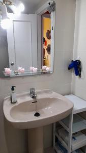 een badkamer met een witte wastafel en een spiegel bij Apartamanto FRENTE AL MAR, un dormitorio con dos camas, mas otra cama abatible en el salon in Benicàssim