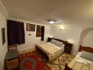 1 dormitorio con cama, mesa y alfombra en Dar benelmahi, en Fez