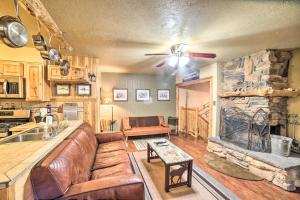 a living room with a couch and a stone fireplace at Rustic Condo with Patio Walk to Angel Fire Resort! in Angel Fire
