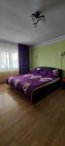 a bedroom with a purple bed and a ceiling fan at Apartament in Iaşi