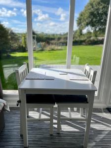 una mesa blanca y sillas en un porche en The Garden Room - A cosy country stay in Cornwall, en Callington