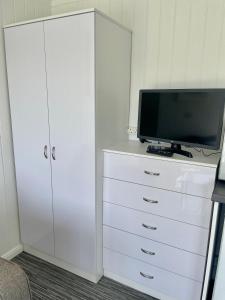 a white dresser with a television on top of it at The Garden Room - A cosy country stay in Cornwall in Callington