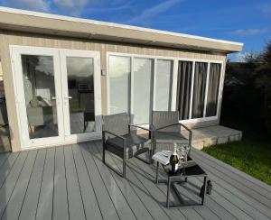 a patio with two chairs and a table on a deck at The Garden Room - A cosy country stay in Cornwall in Callington