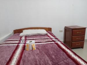 a bed with a purple blanket and a wooden dresser at Hostel Home Trotamundos in Chachapoyas