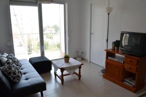 a living room with a couch and a tv at Apartamento junto a playa y cerca de campo de golf in El Perellonet