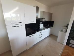 a kitchen with white cabinets and black appliances at Guest house with pool Ante in Vrsi