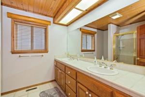 La salle de bains est pourvue de 2 lavabos et d'un grand miroir. dans l'établissement CUSTOM SINGLE STORY CABIN WITH JACUZZI POOL TABLE & BIG GAME ROOM WITH ARCADE games, à Big Bear Lake