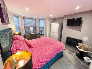 a bedroom with a pink bed and a tv at Olívia Rojo in Cromer