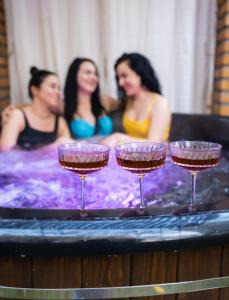 文尼察的住宿－Hotel DENINNA，三个妇女在带酒杯的热水浴池中