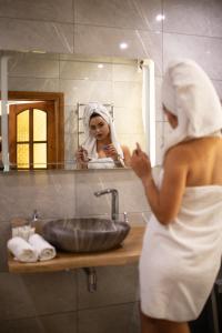 una mujer en una toalla parada frente a un lavabo de baño en Hotel DENINNA en Vínnytsia