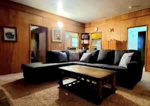 uma sala de estar com um sofá preto e uma mesa de centro em Green Cabin in Big Bear Lake 3 bdr Pets Friendly em Big Bear City