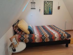 Bett mit einer Bettdecke und einem Tisch in einem Zimmer in der Unterkunft Duplex charmant au coeur de Levroux in Levroux