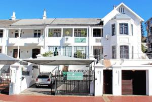 a white building with an umbrella in front of it at The Greenhouse Guesthouse in Cape Town
